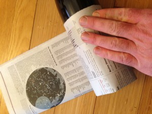 Roll the bottle so the newspaper wraps around it.